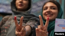 Iranian women show their ink-stained fingers after casting their votes during the presidential election in Tehran on May 19.