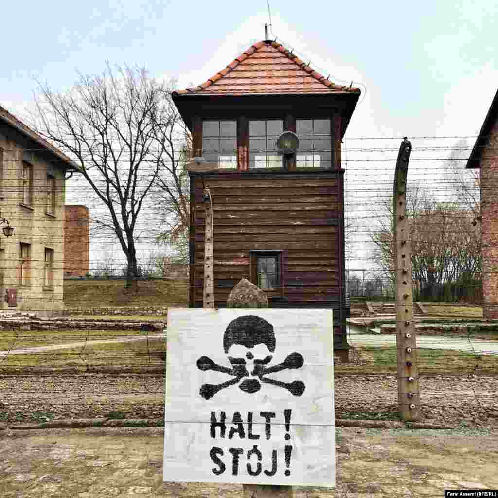 Освенцимдегі тікенек сым қоршаудағы "Тоқта!" деген ескерту жазу.