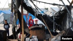 Copii palestinieni privesc urmările unui atac istaelian într-o tabără de refugiați din apropierea orașului Khan Younis, în sudul Fâșiei Gaza.