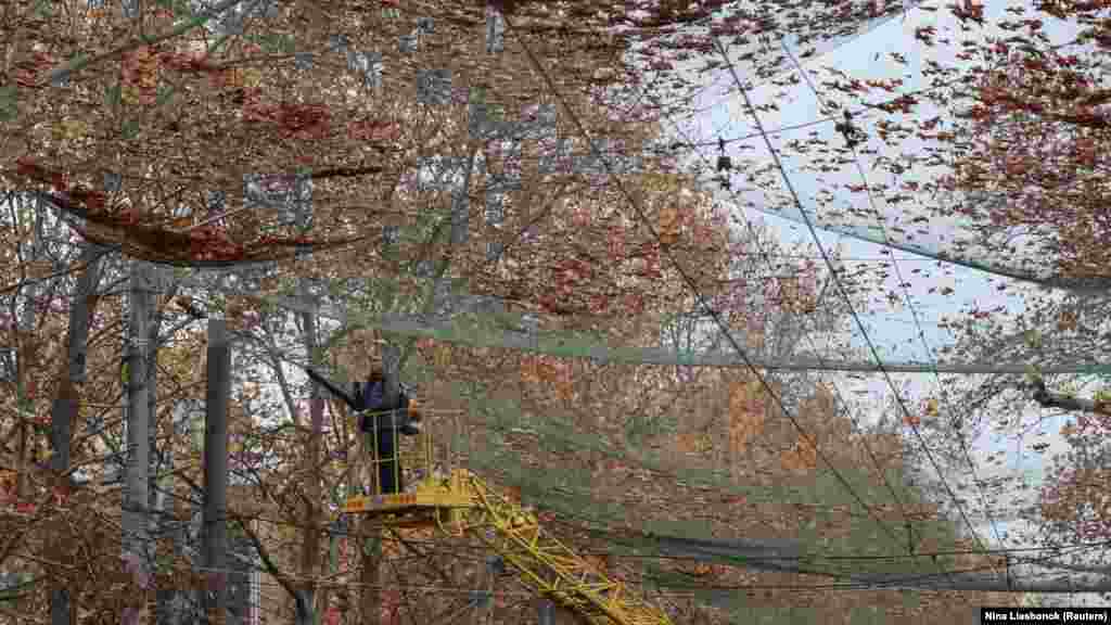 Комунален работник чисти мрежа против дронови инсталирана во Херсон, украински град на првата линија. 11 ноември 2025 година.