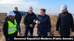 Prim-ministrul Dorin Recean (centru) împreună cu ministrul Energiei, Dorin Junghietu (dreapta), în timpul vizitei pe șantierul de construcție a liniei de înaltă tensiune Chișinău-Vulcănești, 20 februarie 2025.