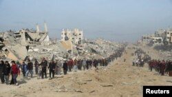 Palestinieni strămutați își croiesc drum printre dărâmături în timp ce încearcă să se întoarcă la casele lor după o amânare a încetării focului între Israel și Hamas cu privire la lista ostaticilor, în nordul Fâșiei Gaza, 19 ianuarie 2025.