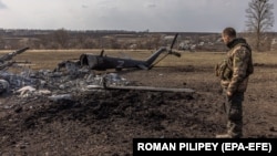 Український військовий біля знищеного російського гелікоптера у відбитому українською армією селі Мала Рогань поблизу Харкова, 31 березня 2022 року