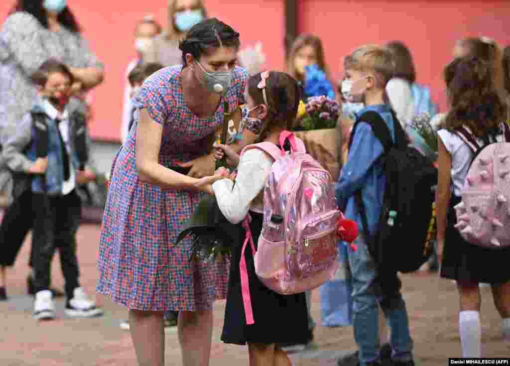 A woman and a girl wearing protective face masks chat as they gather with teachers, parents, and other children in front of a school in the Romanian capital, Bucharest, on September 14 as classes started again after the summer break.&nbsp;​Due to the coronavirus pandemic, most of Romania's schools reopened with students alternating between classroom learning and remote education.