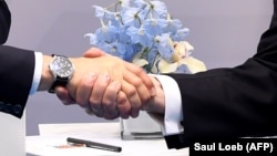 Birleşen Ştatlaryň prezidenti Donald Tramp (sagda) we rus prezidenti Wladimir Putin elleşip salamlaşýarlar.