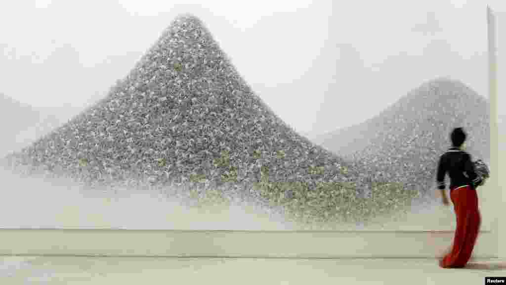 A visitor walks past "Ash Colour Mountains," an acrylic on canvas by Japanese artist Makoto Aida.&nbsp;