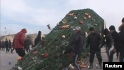 Protesters kick a fallen holiday tree in Zhanaozen on December 16.