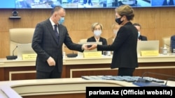 Дарига Назарбаева, дочь экс-президента Нурсултана Назарбаева, получает удостоверение депутата мажилиса из рук председателя ЦИК Берика Имашева, который приходится ей сватом, в столице Нур-Султане, которая названа в честь ее отца. 14 января 2021 года.      