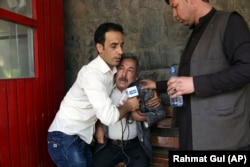 A reporter comforts a man at a hospital who has learned that his son, a journalist, is among those who died in the Kabul bomb attacks.