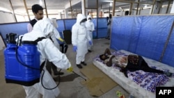 Медики в защитных костюмах осматривают пациента в медицинском центре ВОЗ в Либерии. Монровия, 3 октября 2014 года.