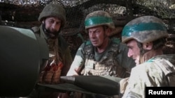 Артилеристи 152-ї ОЄБр ЗСУ заряджають снаряд у самохідну гаубицю M114 на позиції біля Покровська, Донецька область, 15 жовтня 2025 року