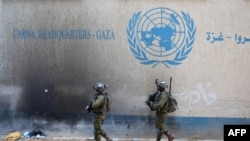 Ushtarët izraelitë duke kaluar pranë selisë së UNRWA-s në Rripin e Gazës.