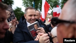 Candidatul naționalist la președinția Poloniei, Karol Nawrocki, ținând în mâini propria sa carte, în timpul unei întâlniri electorale în localitatea Garwolin, pe 5 mai.