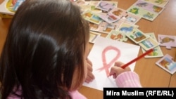 Девочка рисует красную ленточку — символ борьбы со СПИДом —  в центре материнства и детства в Шымкенте. 30 ноября 2010 года.