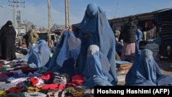 Burqa-clad women sell clothes along a road in Afghanistan (file photo)