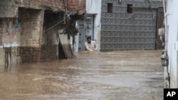 په سوات کې یو کس تر باران وروسته په کوڅه کې له سېلابي اوبو تېرېږي - د اګست ۱۵مې انځور.
