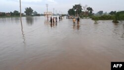 د پنجاب په نارووال کې د سېلاب اوبه پر سړک جمع شوې دي او خلک ورڅخه د تېرېدو هڅه کوي - د اګست ۲۷مې انځور.