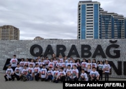 Азербайджанські діти позують на тлі стіни, викладеної з номерів спаленої вірменської техніки