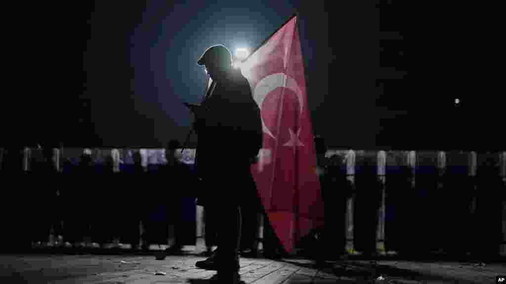 Un manifestant cu un steag turcesc în fața secției de poliție și a clădirii tribunalului din Istanbul, pe 23 martie.
