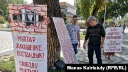 Человек разглядывает плакат с именами 18 человек, находящихся за решеткой или преследуемых, по мнению правозащитников, за свои политические взгляды либо гражданскую позицию. Алматы, 27 августа 2019 года..