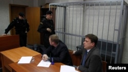 Attorneys of lawyer Sergei Magnitsky sit in front of an empty defendant's cage during a court session in Moscow on March 22.