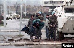 Жителі Сараєва ховаються за БТРом миротворців ООН від снайперського вогню під час облоги міста військами боснійських сербів. Фото 1993 року