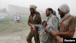 Men carry a person who fainted while queuing up to receive food supplies at a distribution point for North Waziristan's displaced in Bannu.