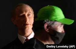A man wearing a face mask to protect against the coronavirus walks past a wax figure depicting Putin at an exhibition in St. Petersburg. Russian authorities on June 30 recorded a new record of 669 confirmed deaths from the virus in a 24-hour period, an increase of 47 from the day before.
