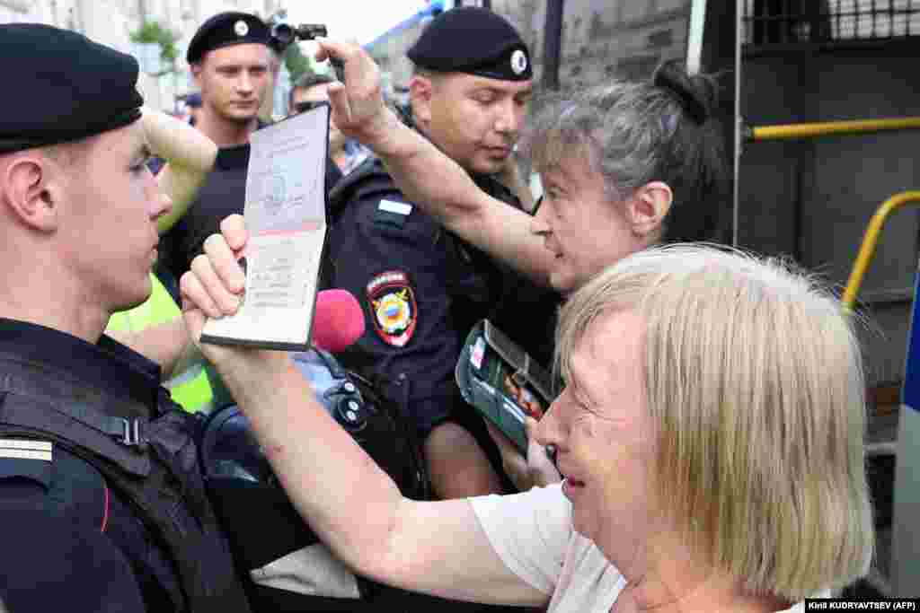 A woman shows her ID to police officers, who were criticized by one civil rights activist for randomly stopping and detaining people "for no reason."