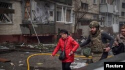 Ukrainian personnel evacuate a woman from an apartment building hit by a Russian missile strike in Sumy, Ukraine on March 24.