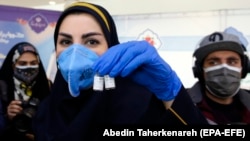 An Iranian health worker displays Iranian ''COV Iran Barekat'' to the media in Tehran before a press conference to announce the launch of the second and third phases of the human trials of the locally made vaccine on March 15.