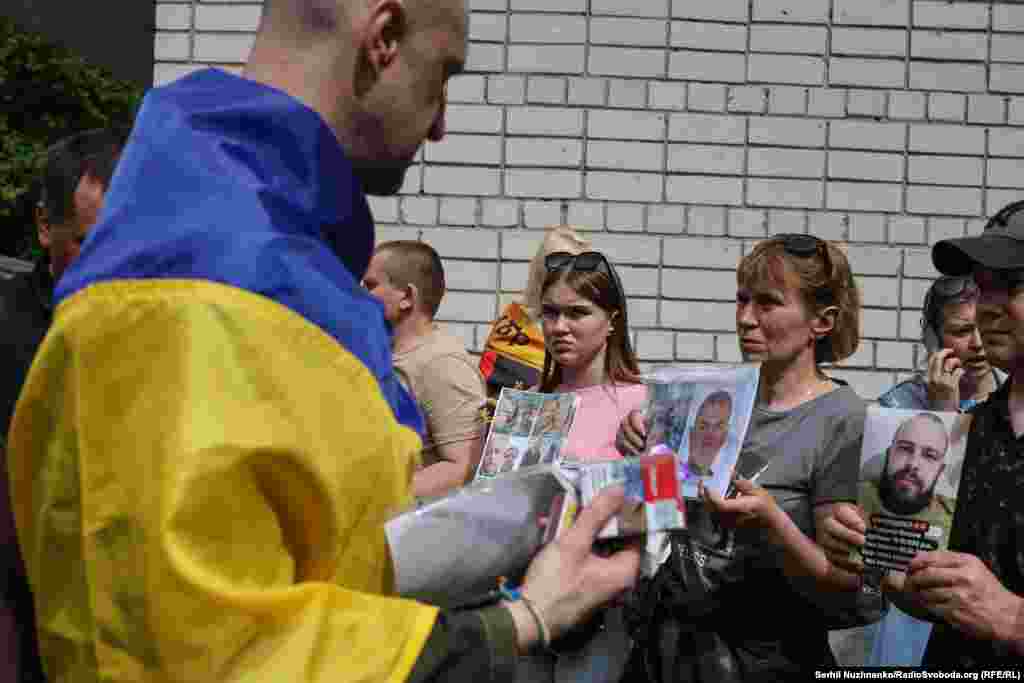 Звільнений з полону військовослужбовець проходить коридором з рідними полонених у надії, що когось впізнає і можливо зможе щось розповісти