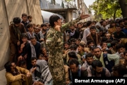 Afghans wait in front of a bank as they try to withdraw money in Kabul on September 12.