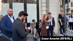 Nicușor Dan în fața sediului de campanie. Geamurile sunt acoperite cu pliante de campanie, expuse invers.