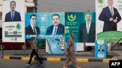 People walk past electoral campaign posters ahead of Iraq's parliamentary elections in central Baghdad on November 6.