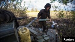 Un militar ucrainean cărând un proiectil de tanc, pe o poziție din apropierea liniei frontului, în afara orașului Bahmut