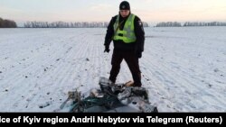 Un polițist ucrainean, lângă o parte a unei rachete de croazieră rusești doborâtă de Forțele armate aeriene, în timpul atacurilor lansate de armata rusă în regiunea Kiev luni, 5 decembrie.