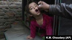 په پاکستان کې یو روغتیايي کارکوونکی یوې ماشومې ته د ګوزڼ واکسیني څاڅکي ورکوي - انځور له ارشیفه. 