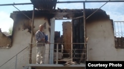 Азимжан Аскаров на фоне сгоревшего во время беспорядков дома. Базар-Коргонский район. Июнь 2010 года. Фото из семейного архива Аскаровых.
