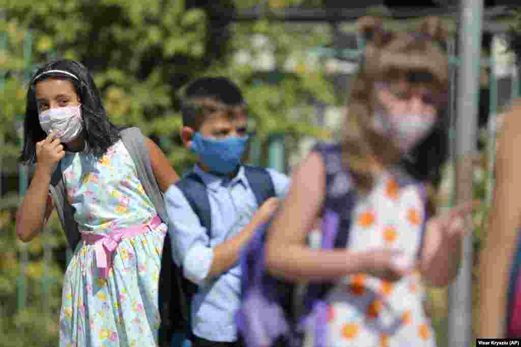 Alegra Bajrami (left), wearing a face mask to protect against the coronavirus, enters a schoolyard on the first day of the new academic year in Kosovo's capital, Pristina. Kosovar schools reopened on September 14 for the first time since March when the COVID-19 crisis began.