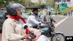 Un bărbat și o femeie merg cu motocicletele în centrul Teheranului (fotografie de arhivă).