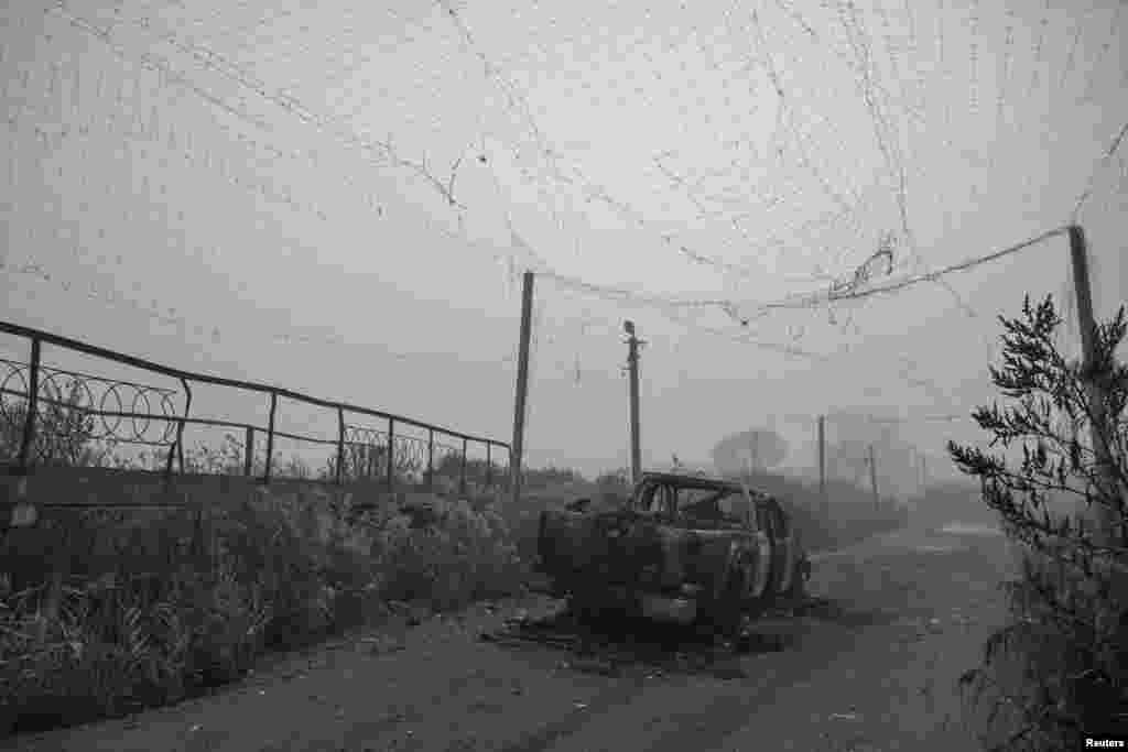 Изгорено возило лежи на средина од улица покриена со мрежа против дронови, во близина на градот Хуљапол во Запорошката област. Мрежата била оштетена од руските напади. 14 ноември 2025 година.