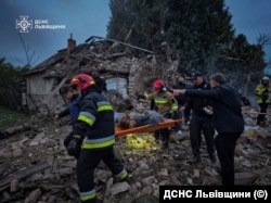 Рятувальники виносять людину, яку знайшли під завалами, зруйнованого російським ударом приватного будинку у селі Лапаївка, Львівщина. Світанок 5 жовтня 2025 року