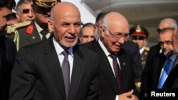 Afghan President Ashraf Ghani (L) walks with Sartaj Aziz, Pakistani national security adviser, after arriving Islamabad on November 14, 2014.