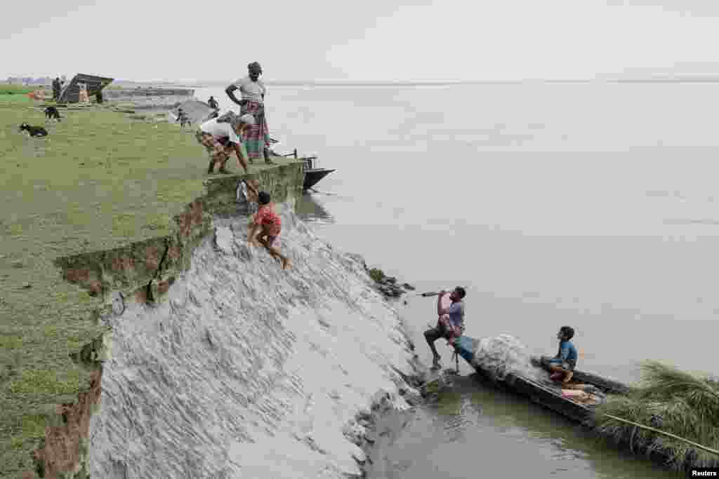 Местные жители на острове в реке Брахмапутра, где они вынуждены переносить свои дома из-за эрозии, Куриграме, Бангладеш, 29 октября 2025 года. REUTERS/Mohammad Ponir Hossain
