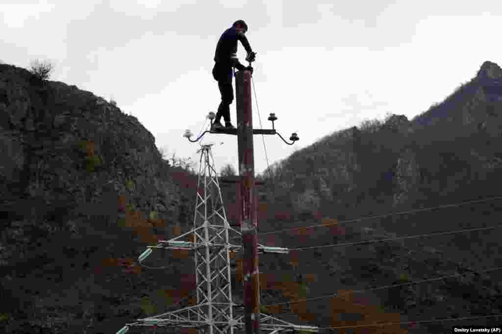 A man removes wiring from a telephone pole in the village of Yekhetnut in the district of Karvachar/Kalbacar.