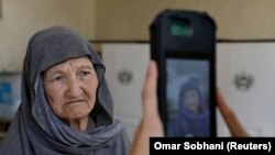 کارمند کمیسیون انتخابات حین گرفتن عکس یک رأی دهنده توسط دستگاه بیومتریک در یکی از مراکز رایگیری در کابل. September 28, 2019