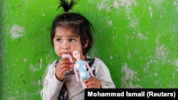 An internally displaced Afghan girl plays outside her shelter in Kabul in May.