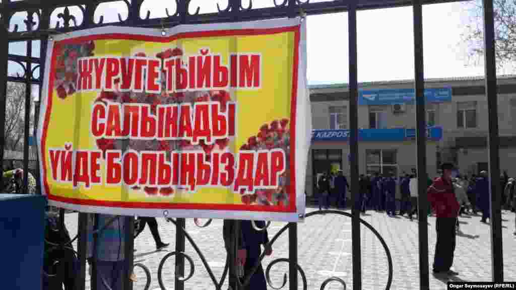 "Қазпошта" бөлімшесі қақпасына ілінген "Жүруге болмайды" деген жазуы бар баннер. Ал бөлімше алдына жұрт таңертеңнен бастап жинала бастады. 6 сәуір 2020 жыл.