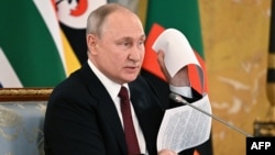 Президент Росії Володимир Путін на зустрічі з делегацією африканських лідерів показує нібито проєкт мирного договору з Україною, який, за його твердженням, був парафований керівником переговорної групи з Києва, 17 червня 2023 року